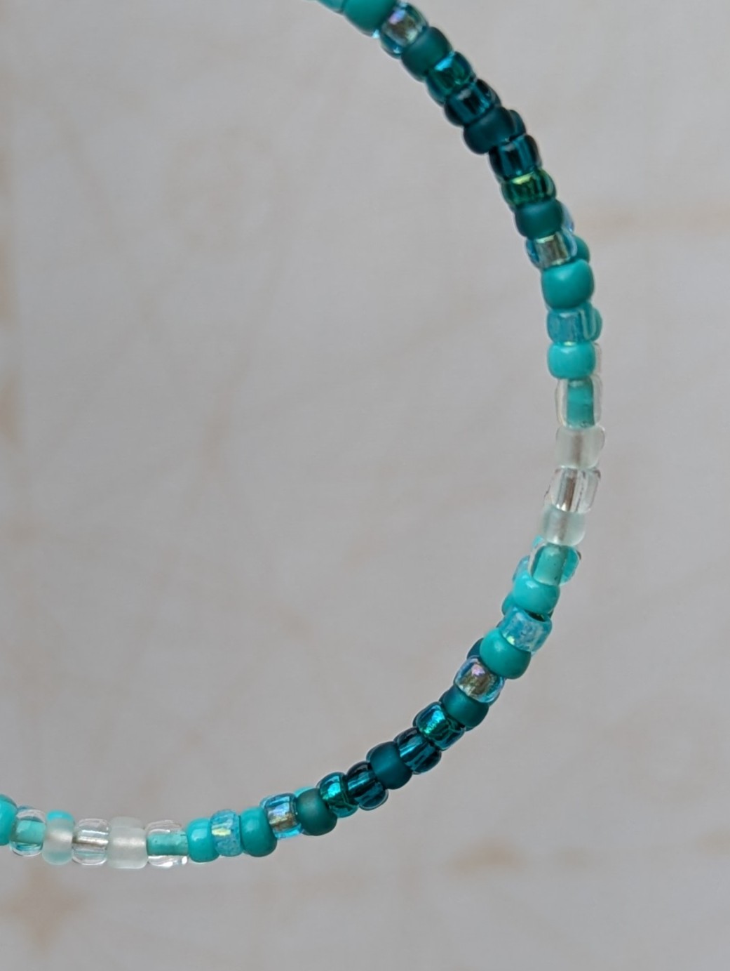 Handmade teal gradient hoop earrings with aqua, turquoise, and ocean-blue glass beads on silver memory wire and sterling silver French hooks.