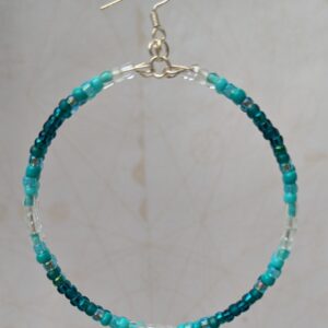 Handmade teal gradient hoop earrings with aqua, turquoise, and ocean-blue glass beads on silver memory wire and sterling silver French hooks.