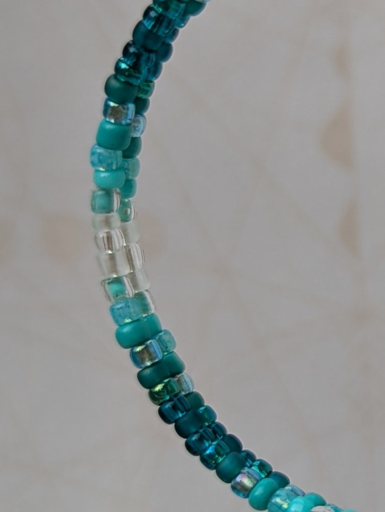Handmade teal gradient hoop earrings with aqua, turquoise, and ocean-blue glass beads on silver memory wire and sterling silver French hooks.