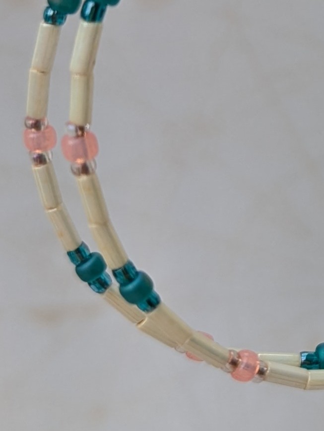 Handmade ivory hoop earrings with blush pink and teal glass bead accents on bronze memory wire and bronze French hooks.