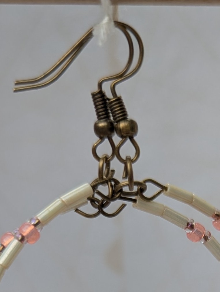 Handmade ivory hoop earrings with blush pink and teal glass bead accents on bronze memory wire and bronze French hooks.
