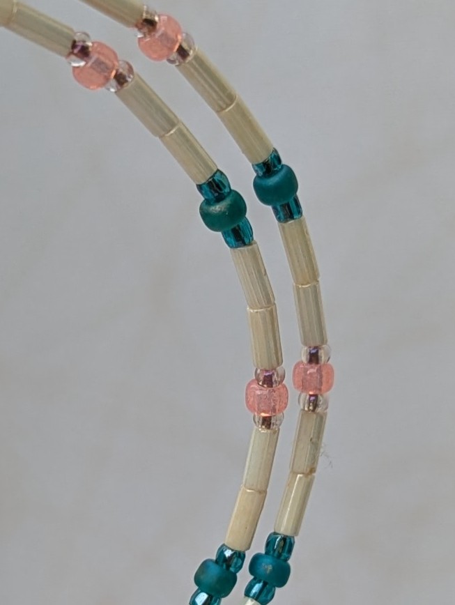 Handmade ivory hoop earrings with blush pink and teal glass bead accents on bronze memory wire and bronze French hooks.