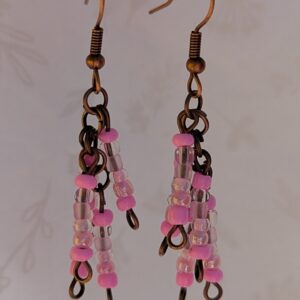 Handmade bronze-tone fringe earrings with soft pink and iridescent blush glass beads hanging in cascading strands from bronze-colored French hooks.
