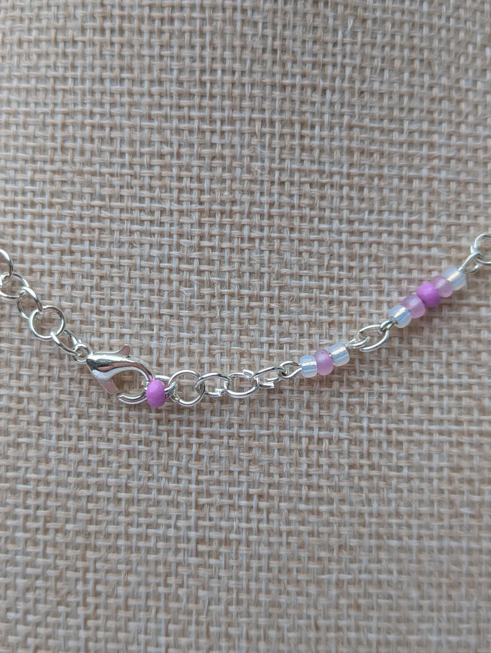 Handmade silver-toned necklace with lavender and pearl-white glass seed beads and five larger lilac stone beads, finished with a silver lobster clasp closure.