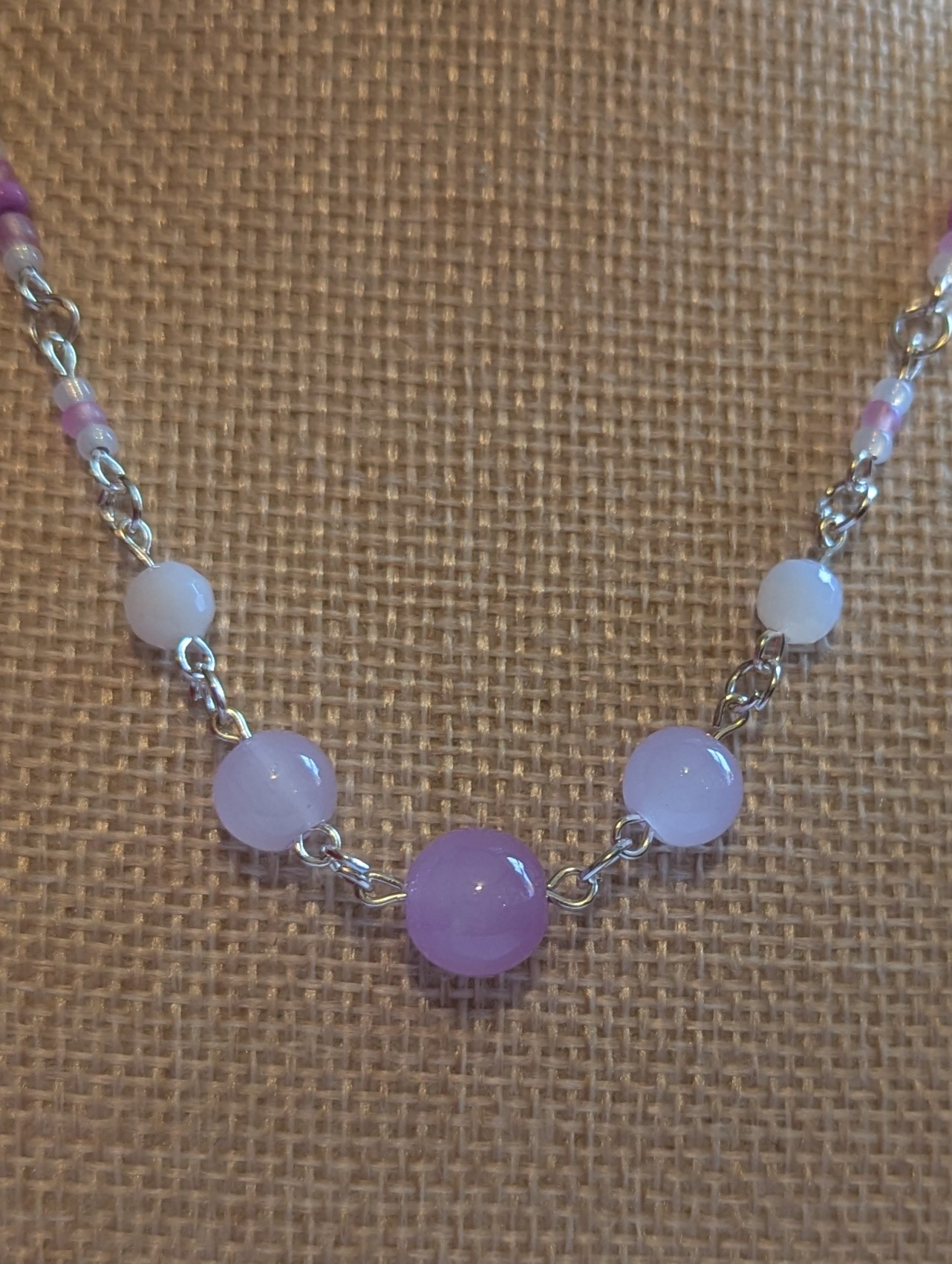 Handmade silver-toned necklace with lavender and pearl-white glass seed beads and five larger lilac stone beads, finished with a silver lobster clasp closure.