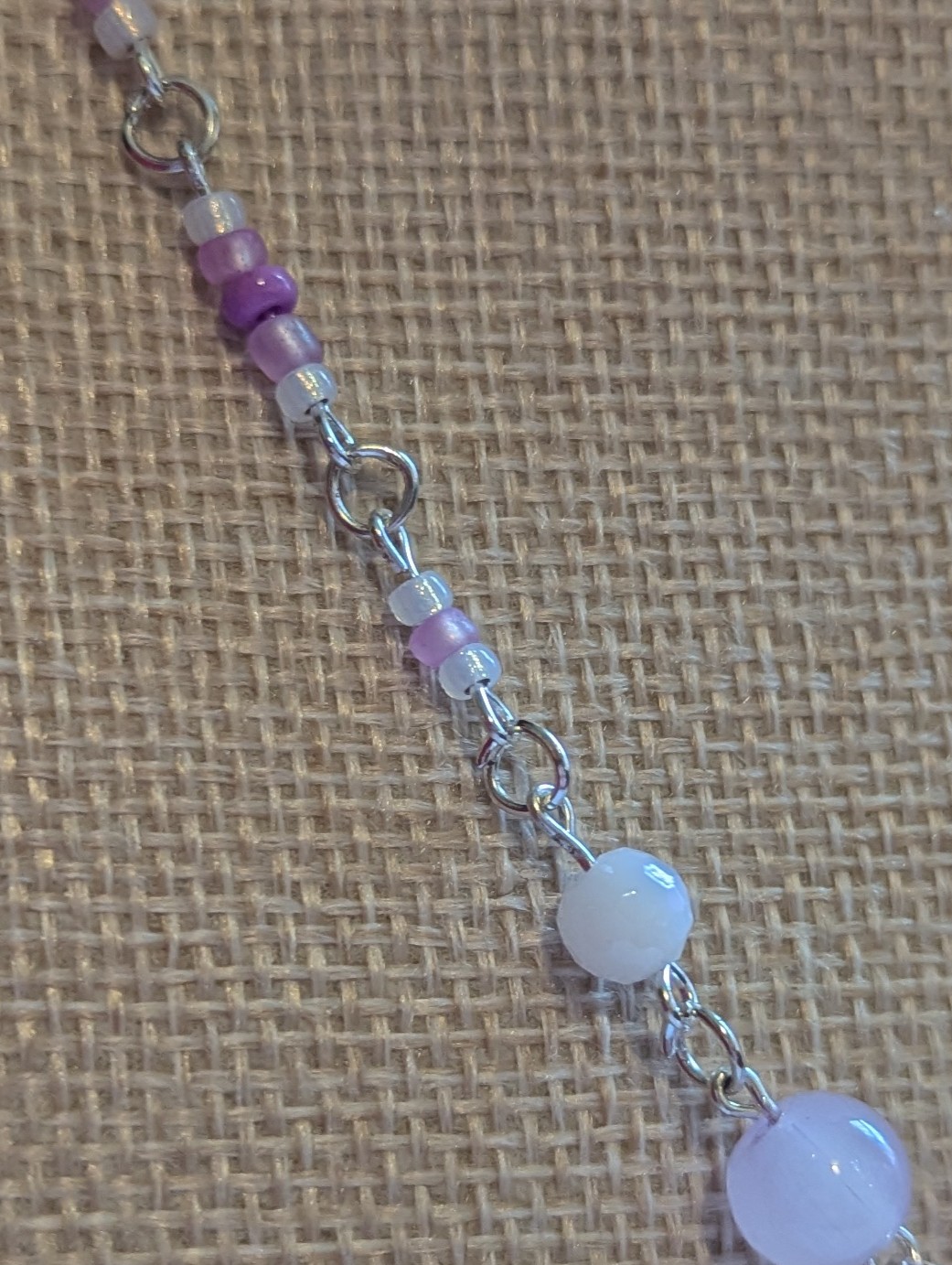 Handmade silver-toned necklace with lavender and pearl-white glass seed beads and five larger lilac stone beads, finished with a silver lobster clasp closure.