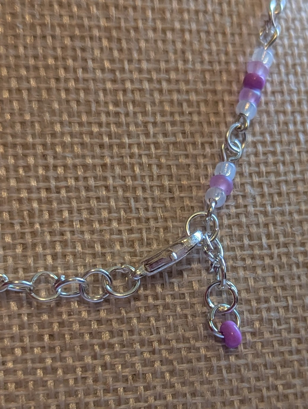 Handmade silver-toned necklace with lavender and pearl-white glass seed beads and five larger lilac stone beads, finished with a silver lobster clasp closure.