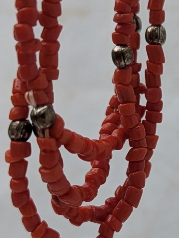 Handmade multi-strand necklace featuring coral red beads on layered thread strands with bronze-colored accent beads and a bronze lobster clasp closure.