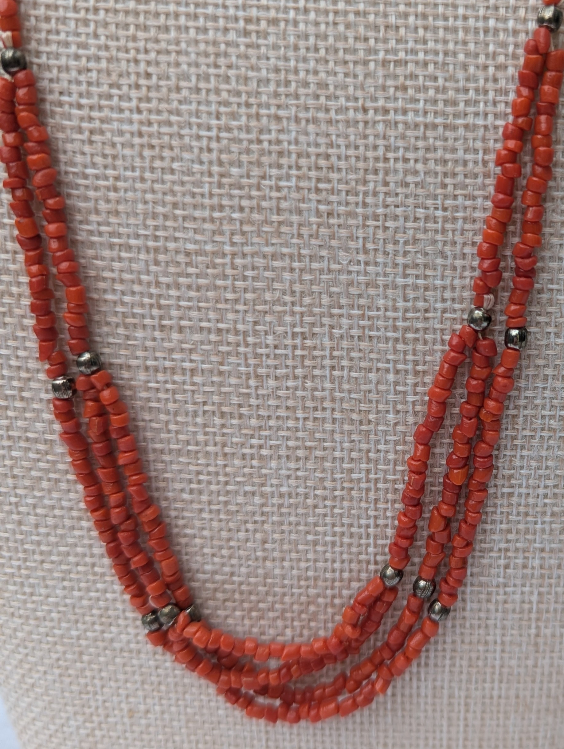 Handmade multi-strand necklace featuring coral red beads on layered thread strands with bronze-colored accent beads and a bronze lobster clasp closure.
