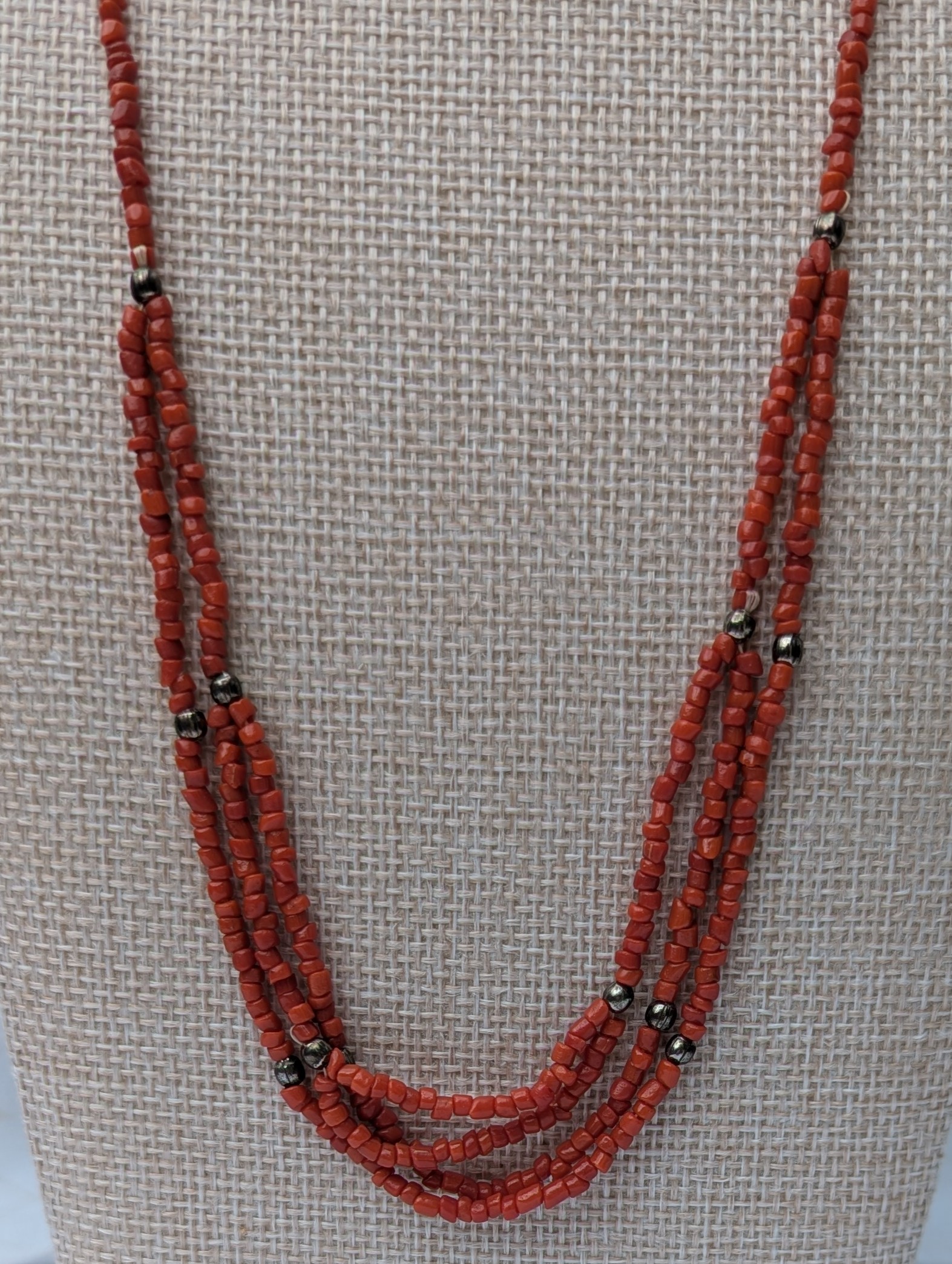 Handmade multi-strand necklace featuring coral red beads on layered thread strands with bronze-colored accent beads and a bronze lobster clasp closure.