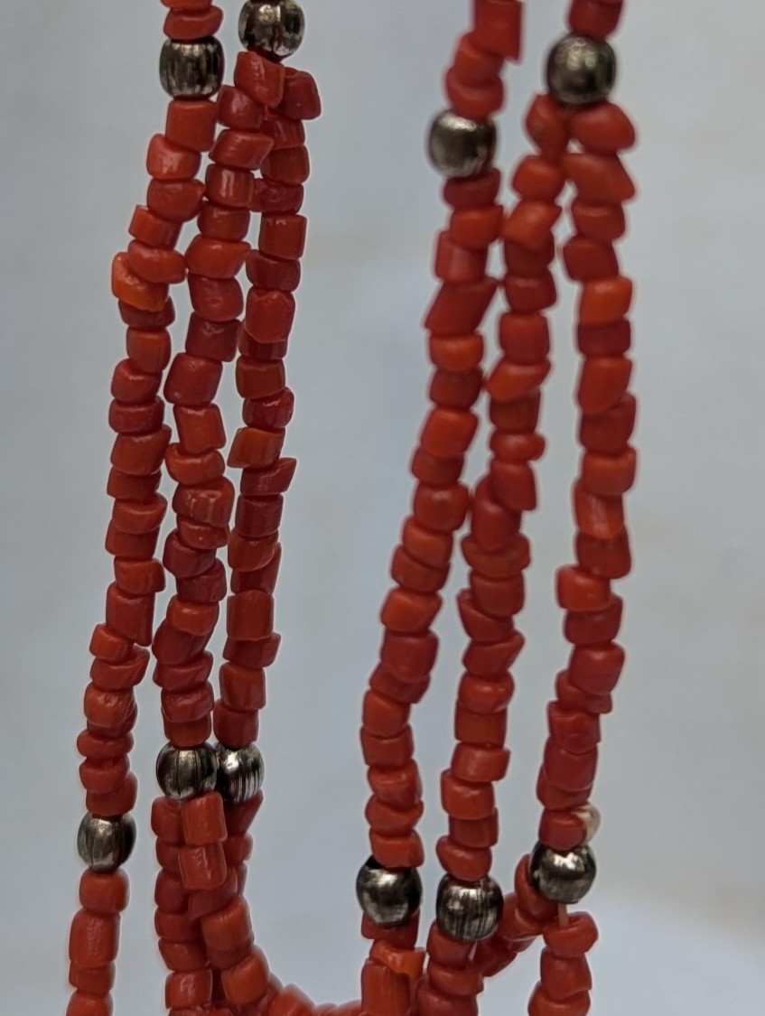 Handmade multi-strand necklace featuring coral red beads on layered thread strands with bronze-colored accent beads and a bronze lobster clasp closure.