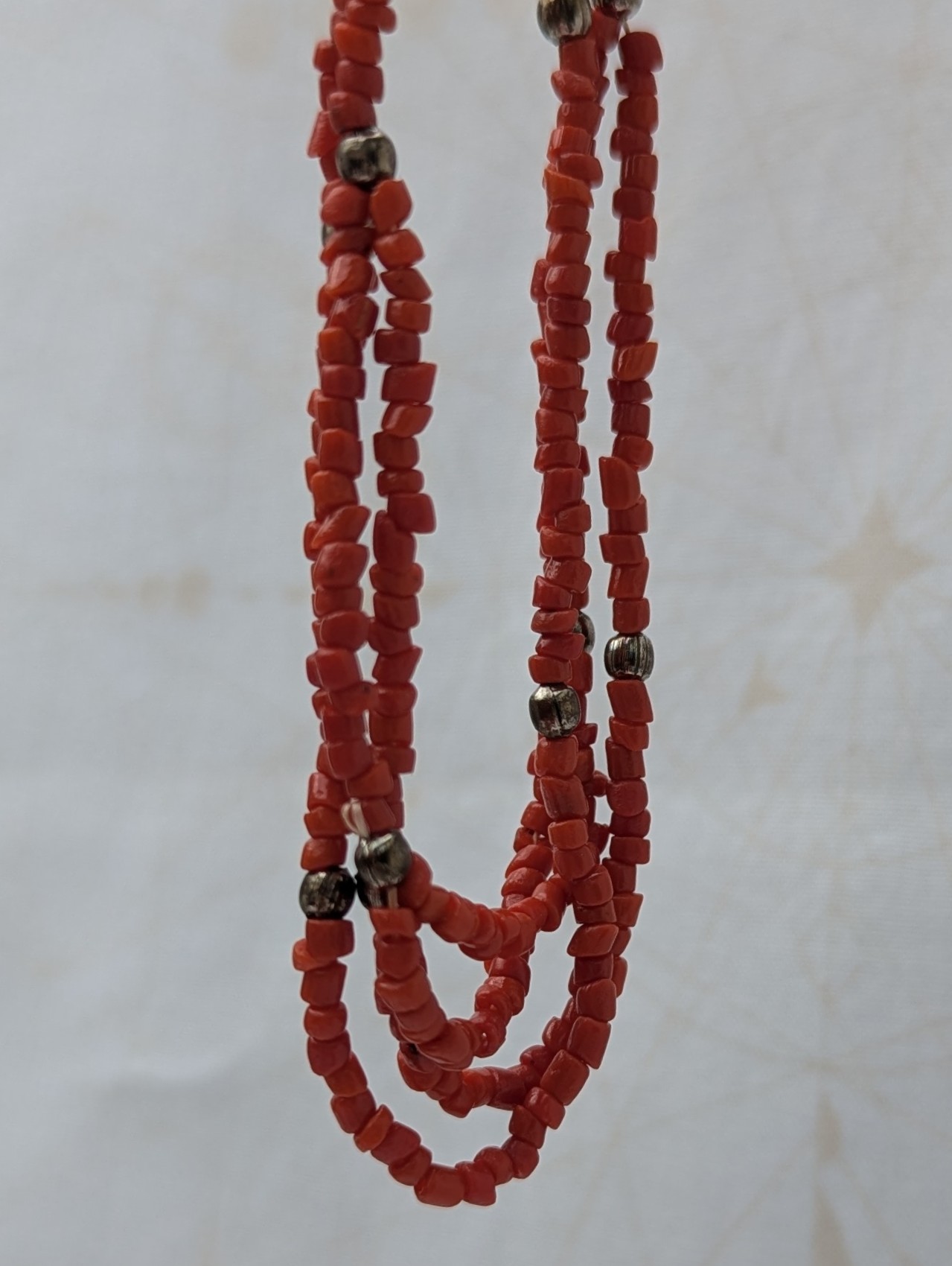 Handmade multi-strand necklace featuring coral red beads on layered thread strands with bronze-colored accent beads and a bronze lobster clasp closure.