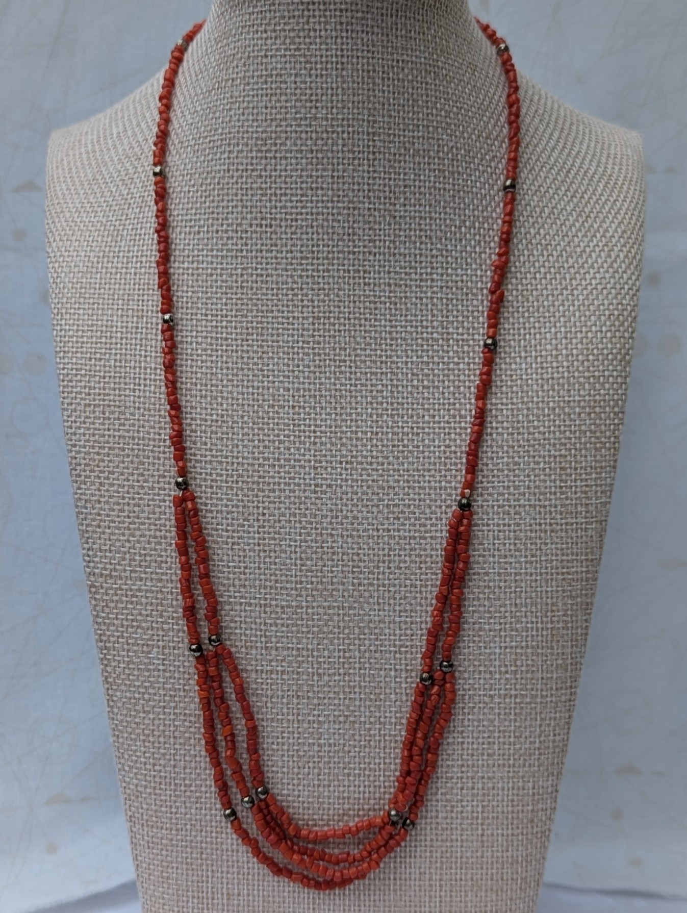 Handmade multi-strand necklace featuring coral red beads on layered thread strands with bronze-colored accent beads and a bronze lobster clasp closure.