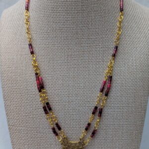 Handmade gold-toned double chain necklace with garnet, burgundy, and deep wine glass seed beads, featuring an ornate gold pendant and lobster clasp closure.