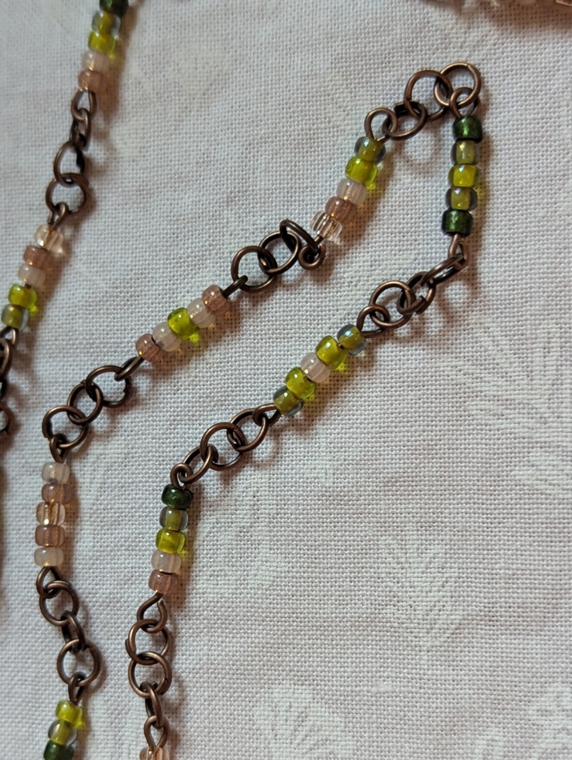 Bronze chain necklace with gradient green glass seed beads in moss, olive, and forest tones with lobster clasp