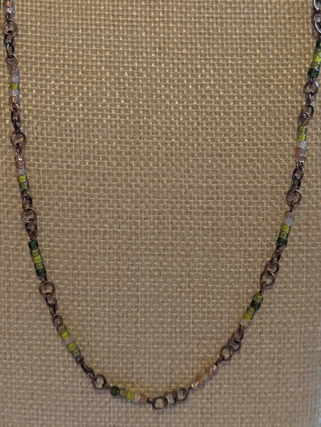 Bronze chain necklace with gradient green glass seed beads in moss, olive, and forest tones with lobster clasp